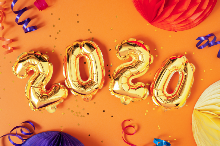 The number "2020" etched out in balloons with party streamers and confetti in the background