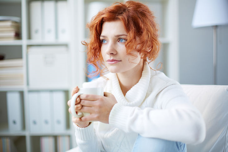 A woman looking concerned while holding a cup of coffee